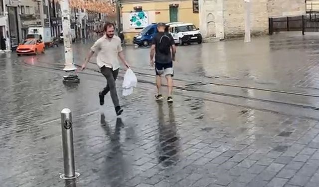 Taksim’de yağmur etkili oldu: Bir vatandaş yağmurdan kartonla korundu